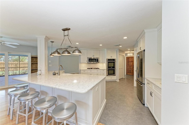 kitchen featuring stainless steel appliances, white cabinets, hanging light fixtures, and a peninsula