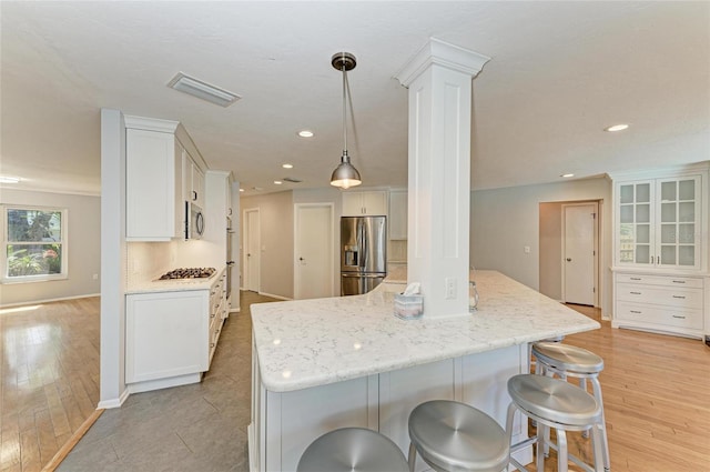 kitchen featuring stainless steel appliances, glass insert cabinets, white cabinetry, and pendant lighting