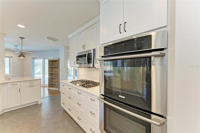 kitchen featuring pendant lighting, stainless steel appliances, visible vents, backsplash, and white cabinets