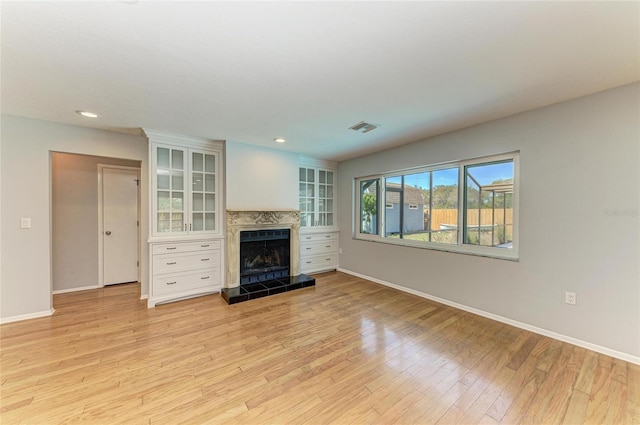 unfurnished living room with light wood-style floors, baseboards, a fireplace, and visible vents