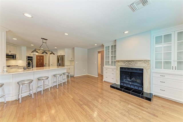 kitchen featuring visible vents, white cabinetry, light countertops, appliances with stainless steel finishes, and glass insert cabinets