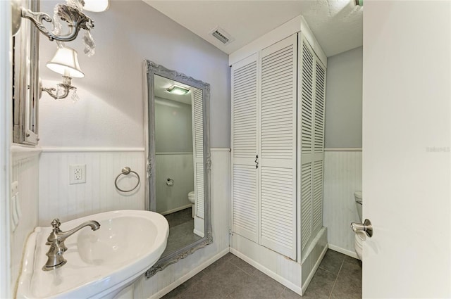 bathroom with toilet, visible vents, a closet, wainscoting, and tile patterned floors