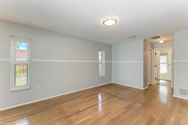 unfurnished room featuring light wood-style floors, visible vents, and baseboards