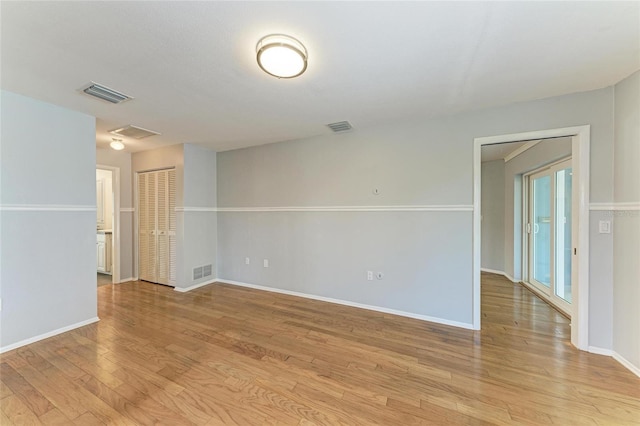 spare room featuring baseboards, visible vents, and light wood finished floors