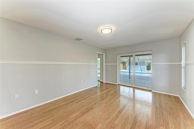 empty room featuring light wood-style flooring, visible vents, and baseboards