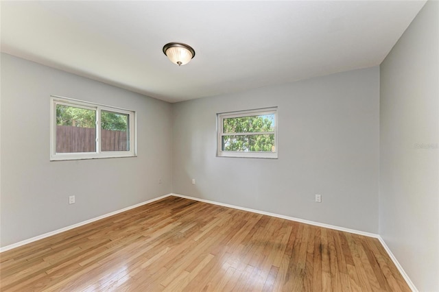 spare room with a healthy amount of sunlight, light wood-style flooring, and baseboards