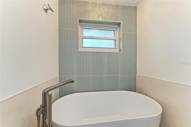 full bath with a soaking tub and tile walls