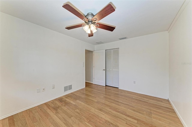 empty room featuring light wood-type flooring, visible vents, and baseboards