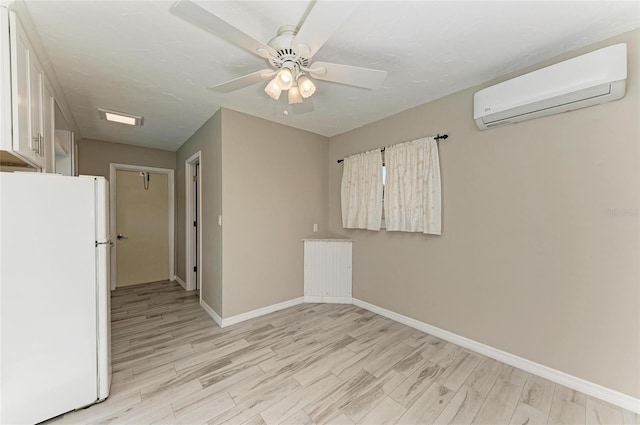 spare room with light wood-style floors, baseboards, a ceiling fan, and a wall mounted air conditioner