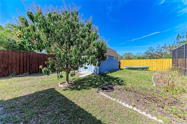 view of yard with a lanai, a storage shed, a fenced backyard, and an outdoor structure