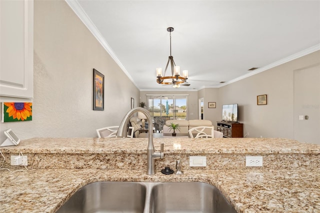 kitchen featuring crown molding, sink, a notable chandelier, and light stone counters