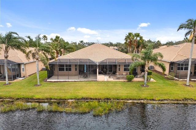 back of house with a yard, a patio area, glass enclosure, and a water view