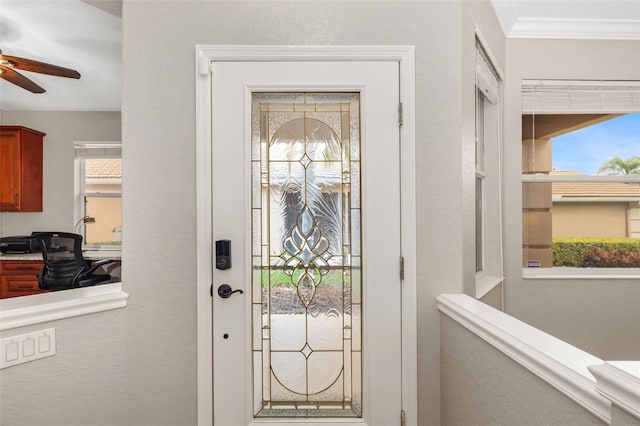 interior space with built in desk, ornamental molding, and a ceiling fan