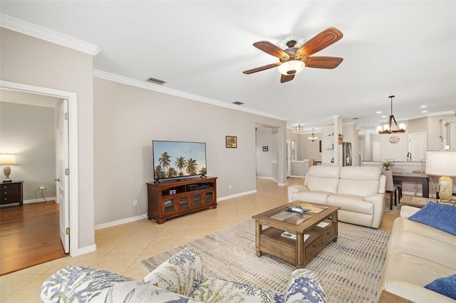 living room with light tile patterned floors, ornamental molding, ceiling fan with notable chandelier, and baseboards