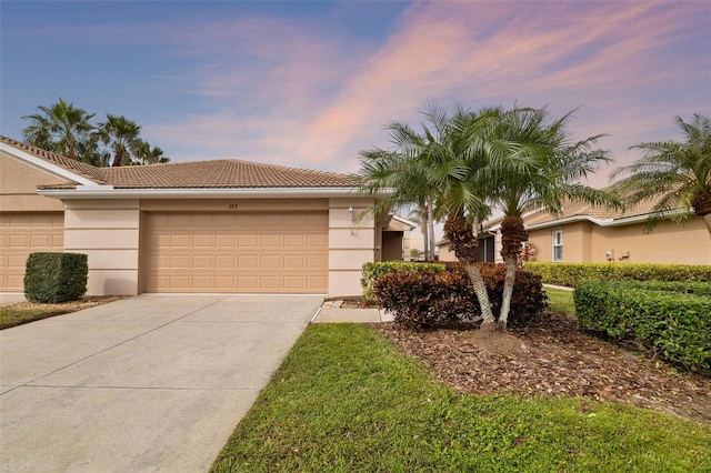 view of front of house featuring an attached garage, a tiled roof, concrete driveway, and stucco siding