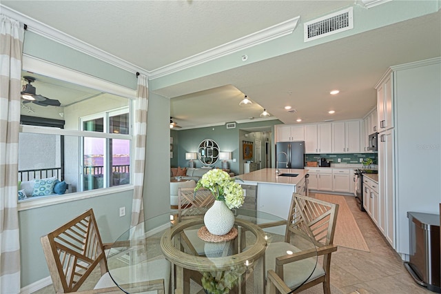 tiled dining space featuring ceiling fan, sink, and ornamental molding