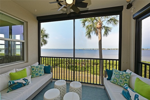 sunroom with ceiling fan and a water view