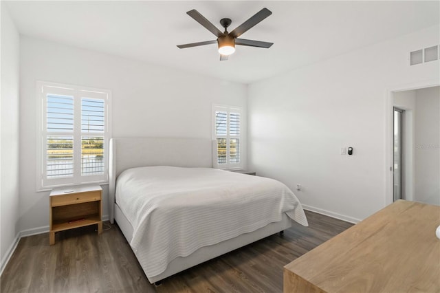 bedroom featuring ceiling fan, dark wood-type flooring, and multiple windows