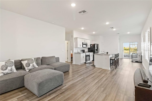 living room with light wood-type flooring and sink