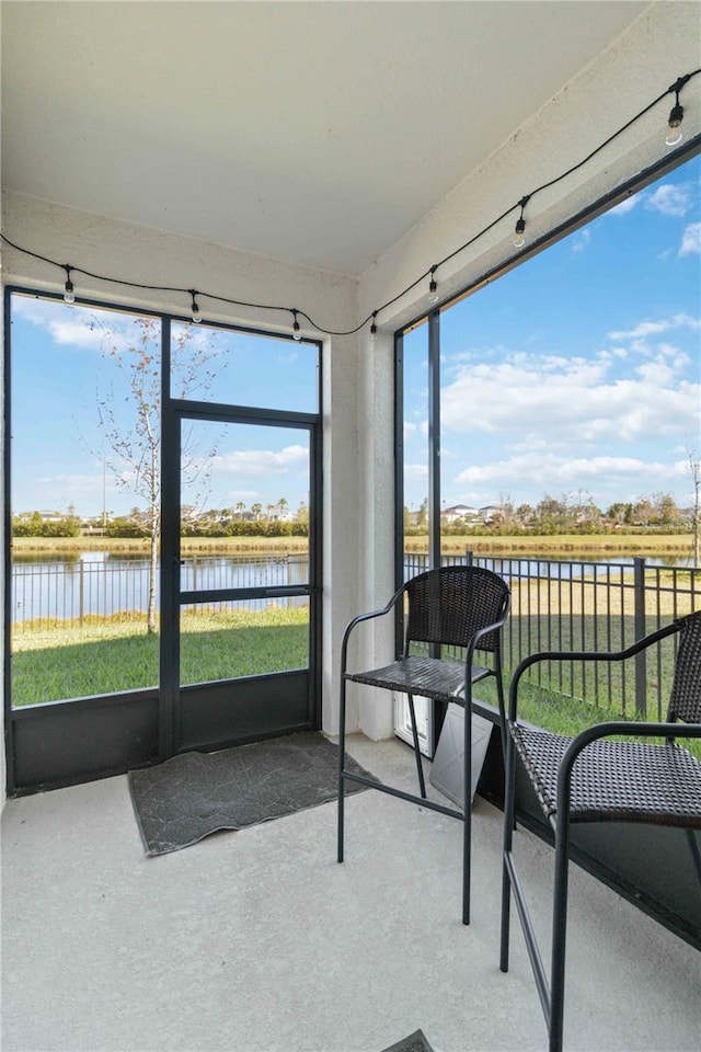 sunroom featuring a water view