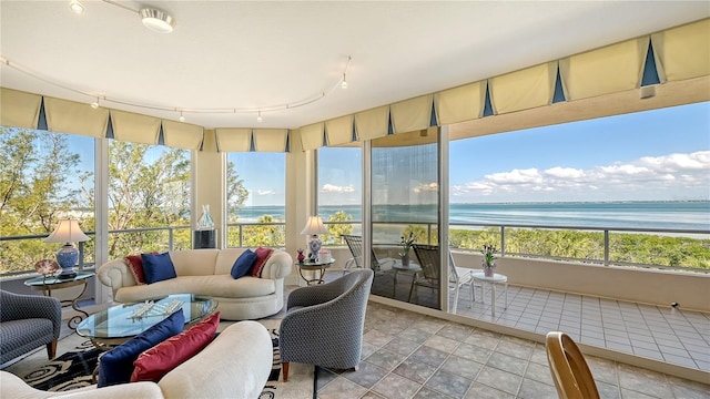 sunroom with rail lighting, a water view, and a wealth of natural light