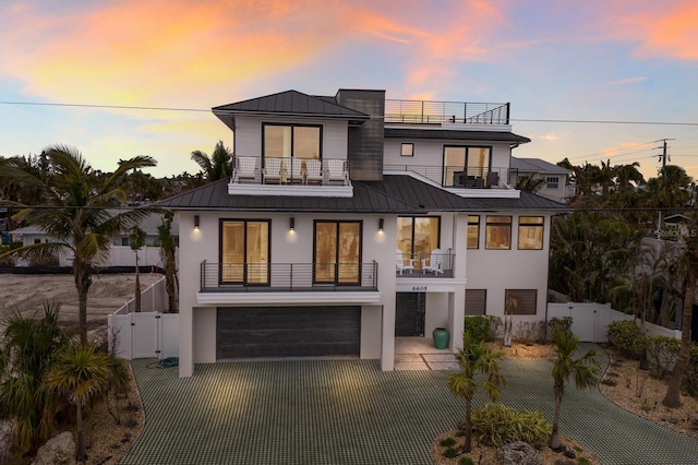 view of front of property with a balcony, a fenced backyard, a standing seam roof, and a gate