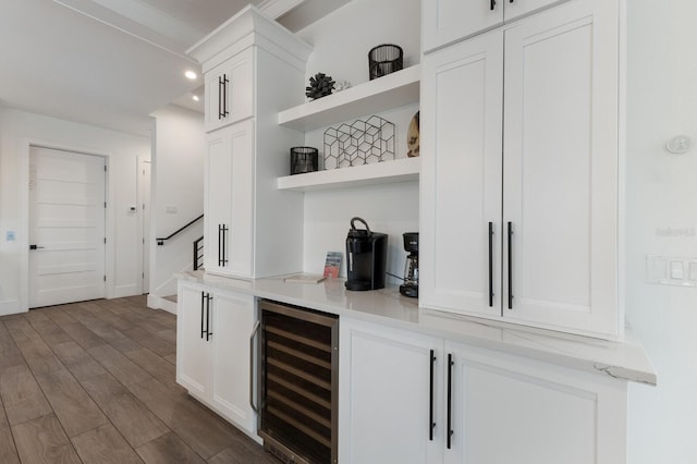 bar featuring light stone counters, dark wood-type flooring, white cabinetry, and beverage cooler