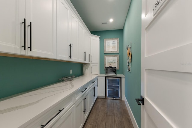 bar featuring light stone countertops, white cabinets, dark hardwood / wood-style flooring, and wine cooler