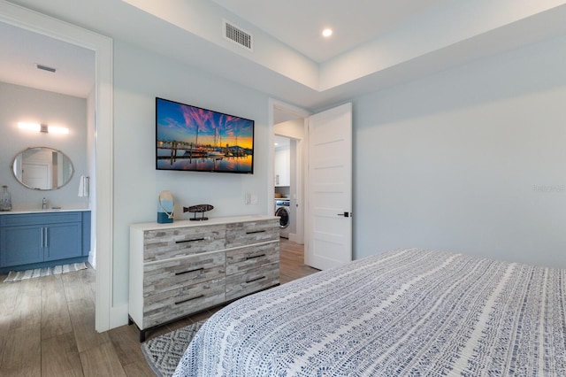 bedroom with washer / dryer, connected bathroom, dark hardwood / wood-style floors, and sink