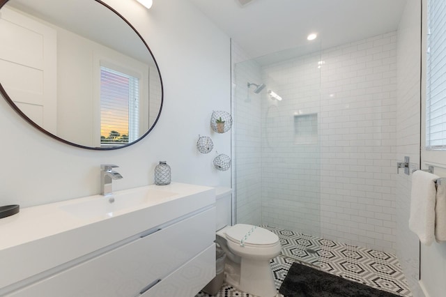 bathroom with toilet, vanity, and a tile shower