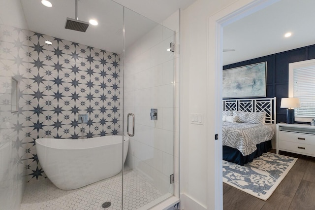 bathroom with hardwood / wood-style flooring, tile walls, and separate shower and tub