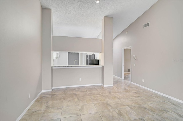 unfurnished living room featuring a textured ceiling, sink, and high vaulted ceiling