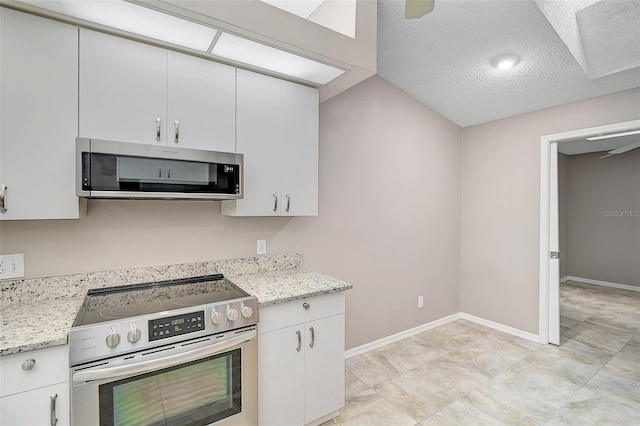 kitchen with a textured ceiling, light stone counters, stainless steel appliances, and white cabinetry