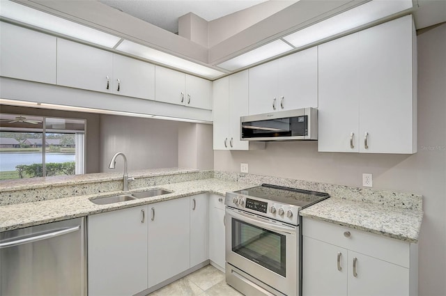 kitchen with sink, light stone counters, stainless steel appliances, and white cabinetry