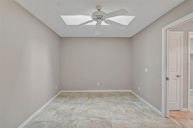 empty room with ceiling fan, a skylight, and a textured ceiling