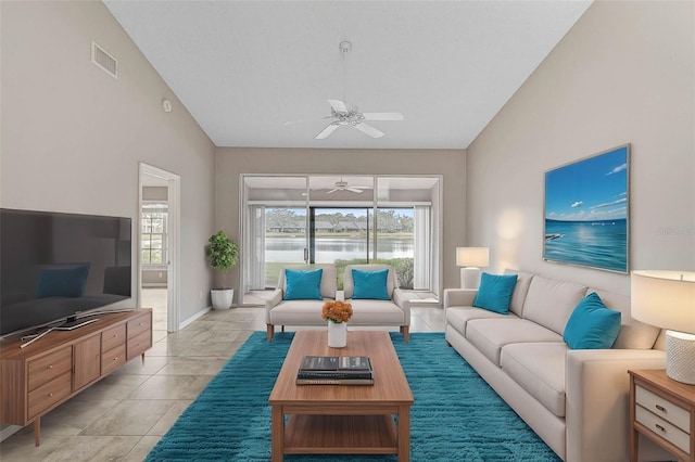 living room featuring ceiling fan, light tile patterned flooring, a water view, and vaulted ceiling