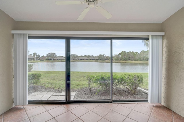 doorway to outside featuring a water view, a healthy amount of sunlight, ceiling fan, and tile patterned floors