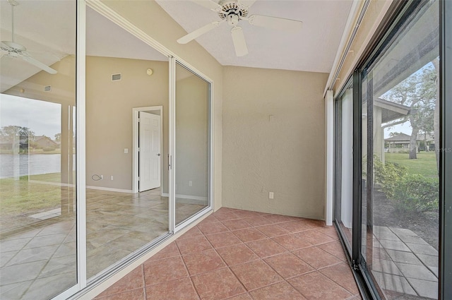 unfurnished sunroom with ceiling fan, a water view, and vaulted ceiling