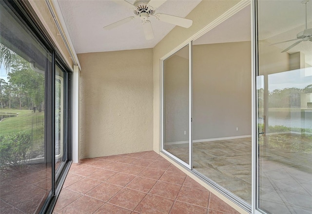 unfurnished sunroom with ceiling fan and a water view