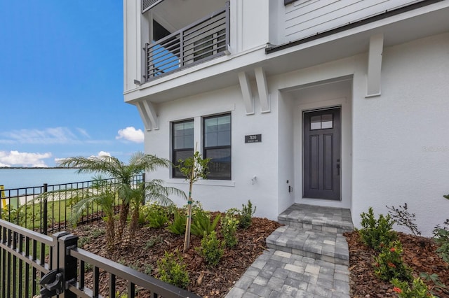 doorway to property with a balcony and a water view