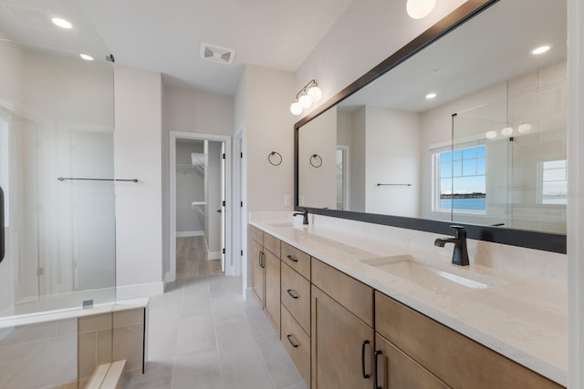 bathroom with vanity, tiled shower, and tile patterned flooring