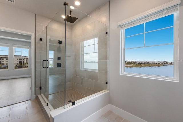 bathroom with a water view, a healthy amount of sunlight, walk in shower, and tile patterned flooring