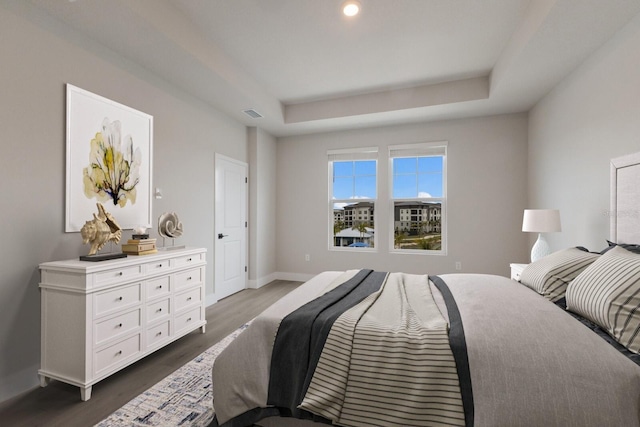 bedroom with dark hardwood / wood-style flooring and a raised ceiling