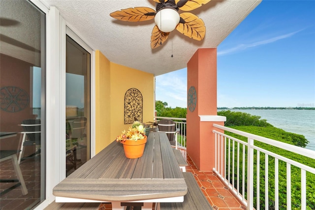 balcony with ceiling fan and a water view