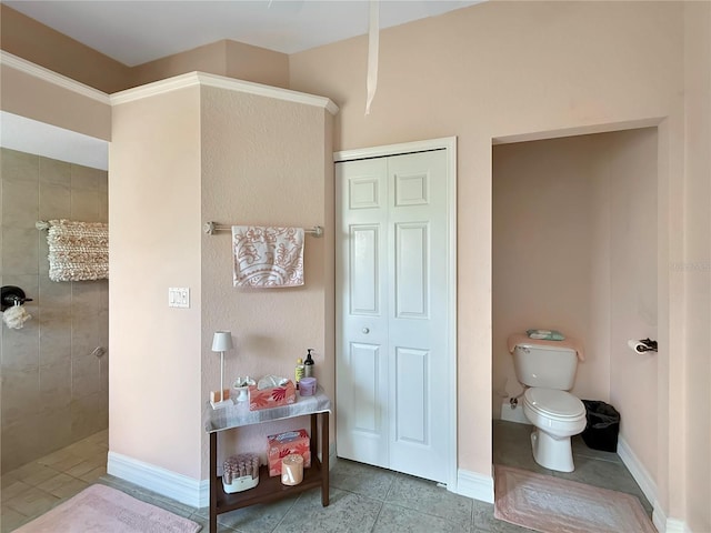 bathroom with tile patterned floors, tiled shower, and toilet