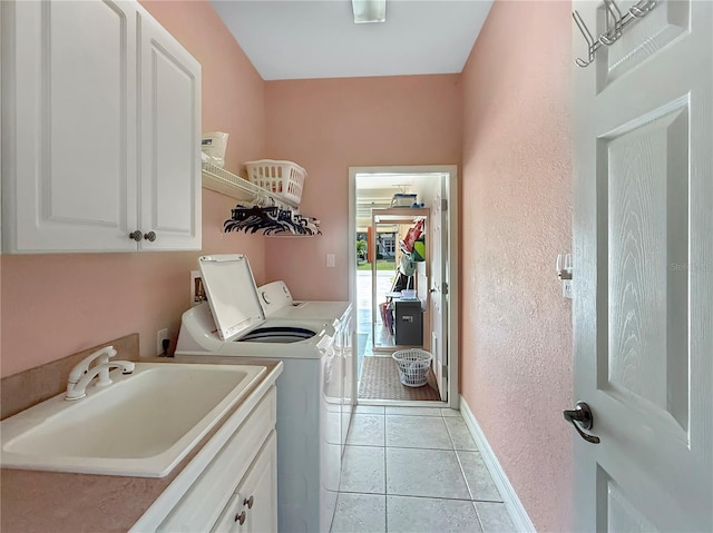 laundry room featuring washing machine and dryer, sink, light tile patterned floors, and cabinets