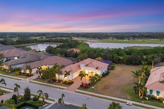 aerial view at dusk featuring a water view