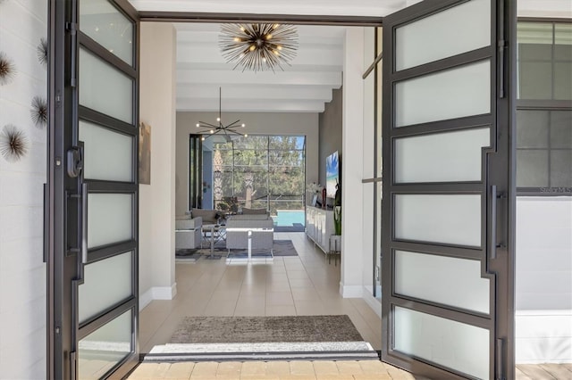 tiled foyer featuring a notable chandelier and beam ceiling