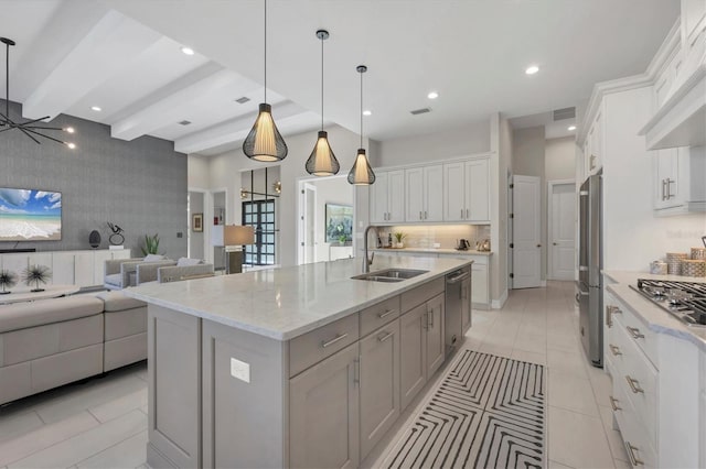 kitchen featuring stainless steel appliances, a large island with sink, pendant lighting, sink, and white cabinetry