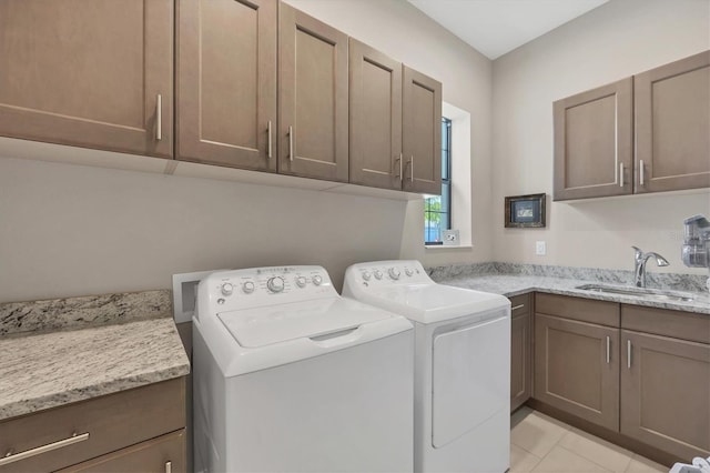 washroom featuring sink, cabinets, washing machine and dryer, and light tile patterned floors